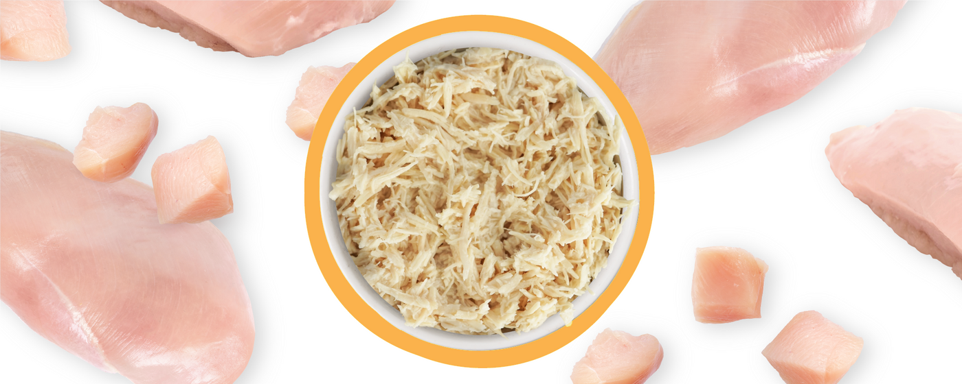 A bowl of shredded chicken is surrounded by raw chicken breasts and cubes, all displayed on a white background.