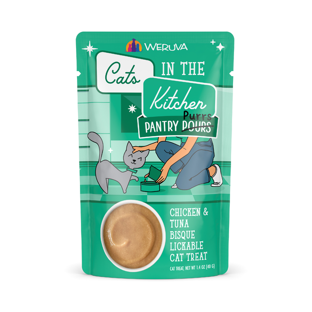 A teal Cats in the Kitchen Chicken & Tuna Bisque pouch features an illustration of a person feeding a gray cat and a circular window displaying the lickable treats inside.