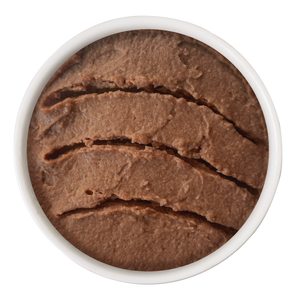 A white bowl filled with Cat Person Beef & Tuna Juicy Paté, consisting of smooth, brown beef and tuna with horizontal indentations.