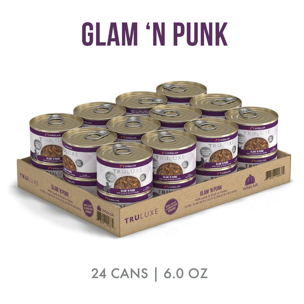 A cardboard tray holds 24 cans of TruLuxe Glam 'N Punk cat food, featuring purple and white labels. The cans contain 6.0 oz each, made with New Zealand grass-fed lamb and wild-caught tuna. Text reads: 24 cans | 6.0 oz.