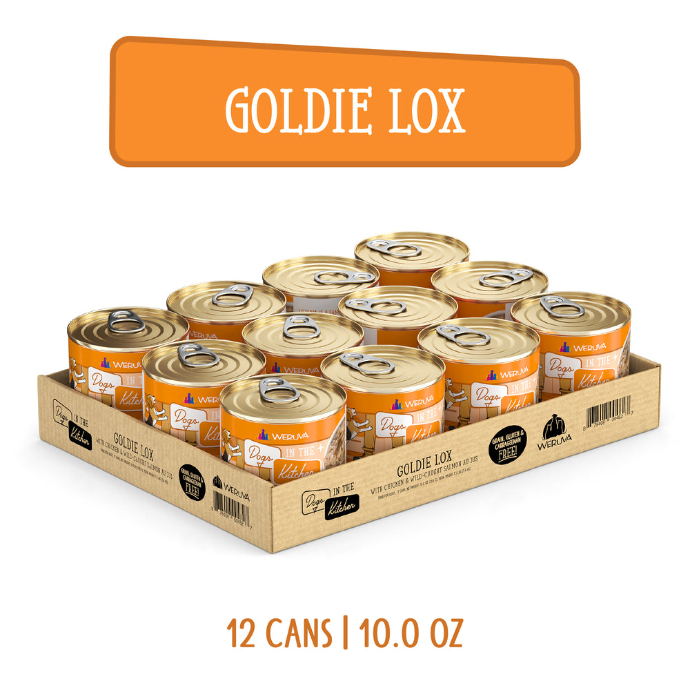 A cardboard tray holds 12 cans of Dogs in the Kitchen Goldie Lox, each 10.0 oz., made with cage-free chicken and wild-caught salmon. The orange and white label matches the large orange GOLDIE LOX sign above the tray.