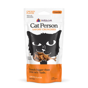 A bag of Cat Person Chicken Savory Crunchies cat treats comes in a white and orange package with a black cat face illustration and crunchy treats visible through a mouth-shaped transparent window.