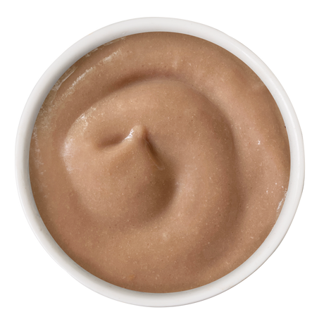 A white bowl of light brown bisque, viewed from above, shows a creamy swirled texture—just like the smooth consistency found in Cats in the Kitchen Chicken & Salmon Bisque with Senior Support for cats.