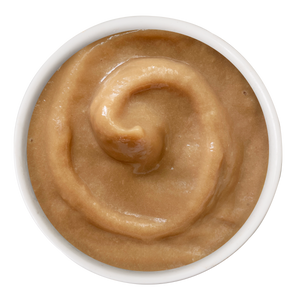 A small white bowl filled with Cats in the Kitchen Tuna Bisque, a smooth, light brown treat for cats swirled in a spiral pattern—delicious and tempting, just like your cat’s favorite tuna snack.