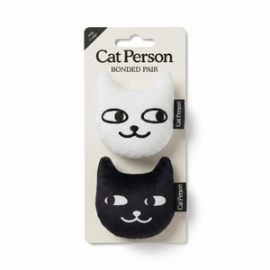 The Weruva Cat Person Bonded Pair Catnip Toy includes two plush cat toys, one white and one black, with embroidered faces and “Cat Person” tags—perfect for interactive play with your feline friend.