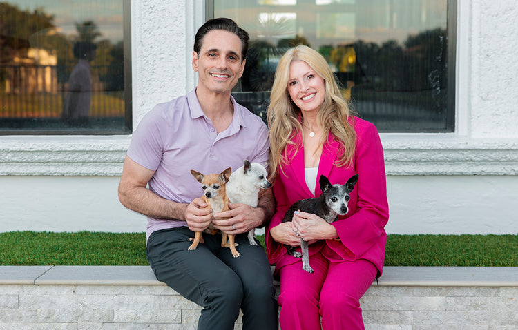 a man and woman sitting on a bench with dogs