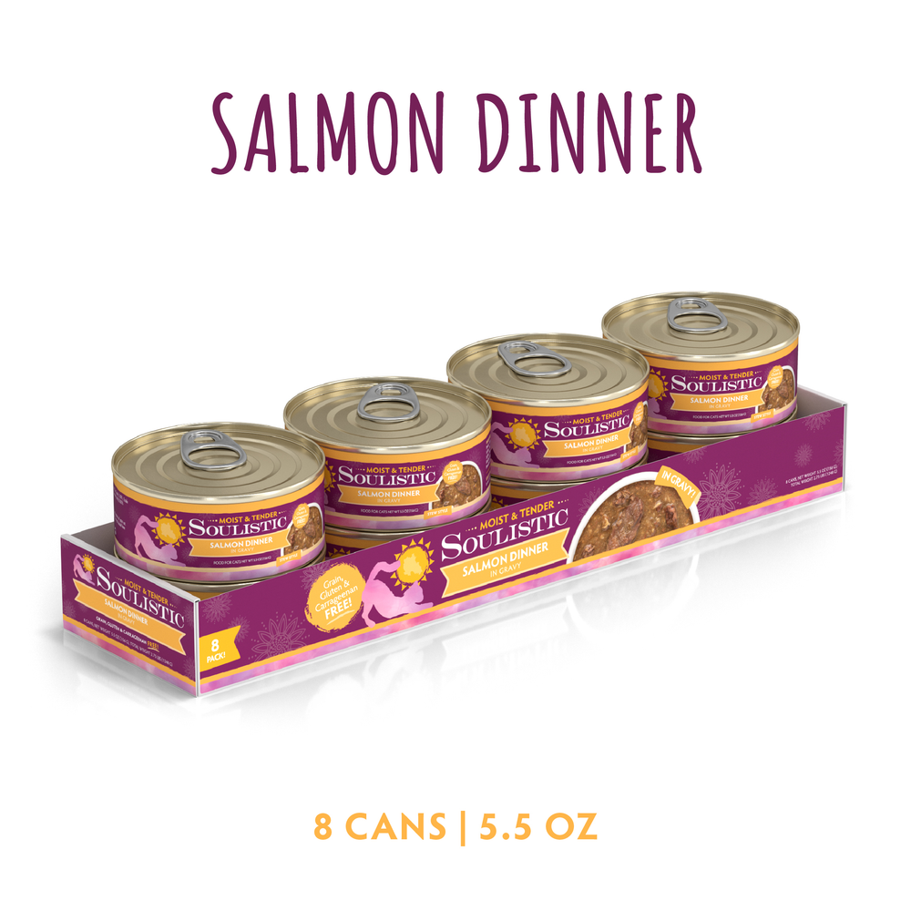 A purple tray displays eight 5.5 oz cans of Soulistic Salmon Dinner in Gravy cat food, made with wild-caught salmon. The label says “Salmon Dinner in Gravy” at the top and "8 cans | 5.5 oz" at the bottom.