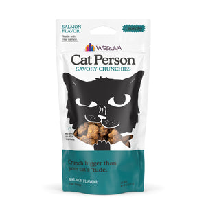 A bag of Cat Person Salmon Savory Crunchies low calorie cat treats, featuring a black cat on a white and teal package with a clear window showing the treats. Supports a shiny coat.