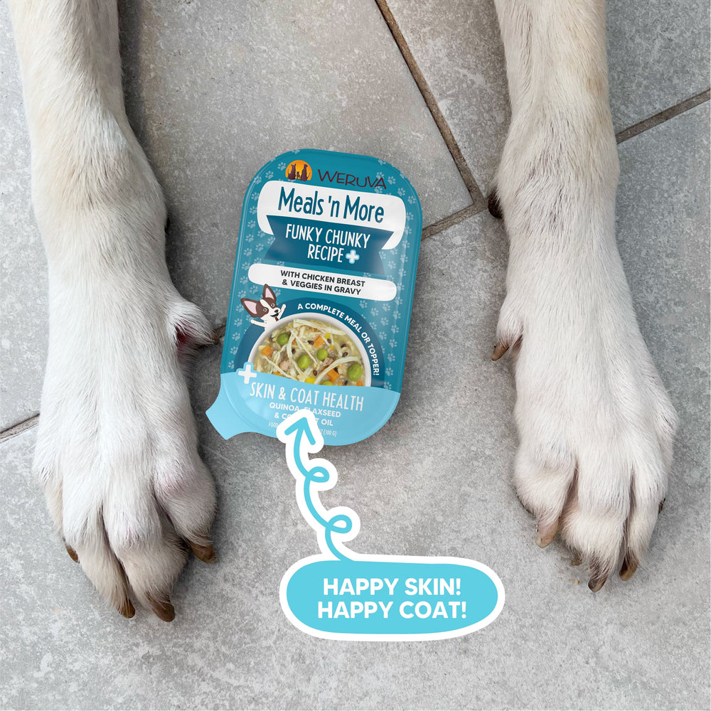 A pack of Weruva Funky Chunky Recipe Plus dog food sits on a tiled floor between two white dog paws, featuring a label that reads Happy Skin! Happy Coat! with an arrow pointing to its skin & coat health benefits.